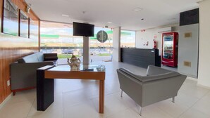 A modern lobby with a reception desk, seating area, and a Coca-Cola vending machine.