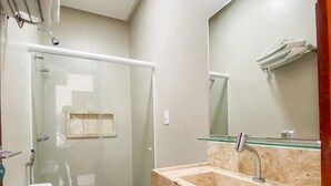 A modern bathroom with a glass-enclosed shower, a toilet, and a sink with a marble countertop.