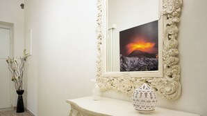 A hallway with a cream-colored console table, a mirror with a floral frame, and a vase with branches. - Apartment Enea Centralissimo Rinnovato, Vicinissimo Alla Stazione e Attrazioni (Pompei)