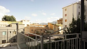 A residential building with multiple balconies, a staircase, and a view of surrounding buildings and mountains. - Apartment Enea Centralissimo Rinnovato, Vicinissimo Alla Stazione e Attrazioni (Pompei)