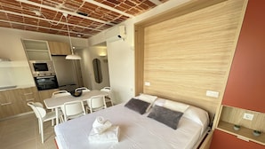 A modern bedroom with a large bed, a wooden headboard, a small bedside table, and a built-in desk area. - Agi Arago 271 Apartamento for rent in Roses Girona. (Roses)