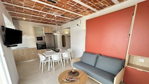 A modern living space with a dining area, a sofa, and a TV mounted on the wall. - Agi Arago 271 Apartamento for rent in Roses Girona. (Roses)