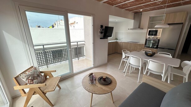 Um apartamento moderno com varanda, área de jantar e cozinha.