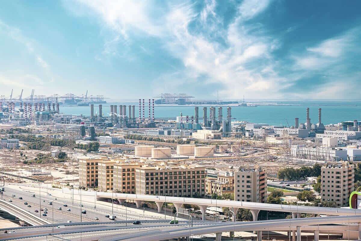 A cityscape with a large building complex, multiple high-rise structures, and a busy highway.