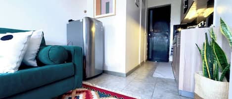 Una sala moderna con un sofá color turquesa, una alfombra estampada y un refrigerador.