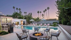 Un espace aménagé au bord de la piscine, avec des chaises longues, un foyer et une piscine.
