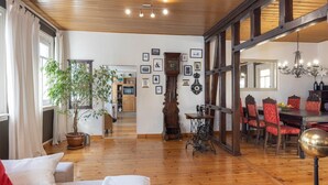 Een ruime woonkamer met houten vloeren, een eethoek met rode fauteuils, en een grote spiegel boven de eettafel.