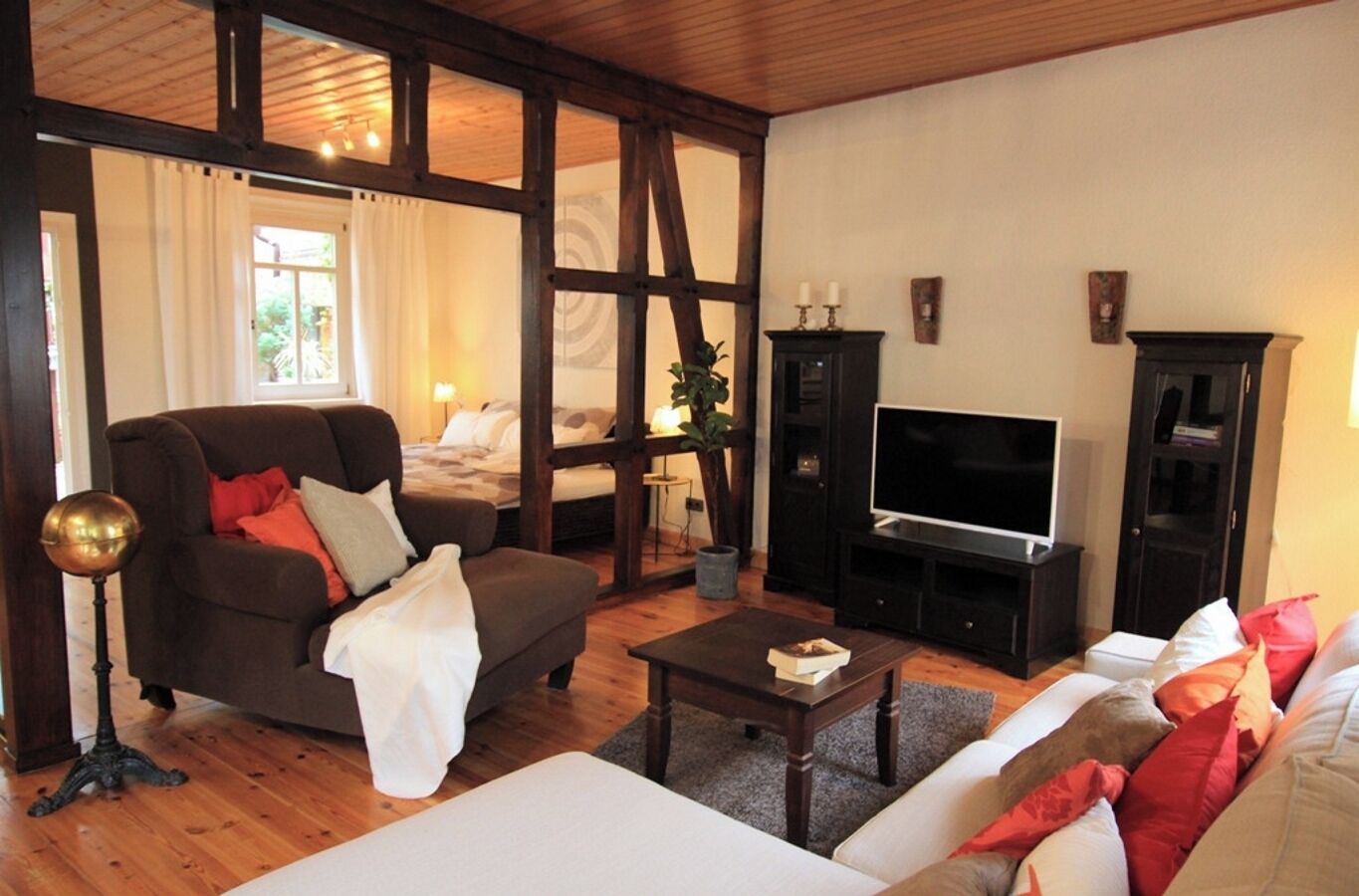 Ein gemütliches Wohnzimmer mit einer Couch, einem Couchtisch, einem Fernseher und einem Bett.