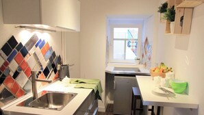 Uma cozinha compacta com pia, um refrigerador pequeno e uma janela.