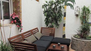 A wooden sofa with cushions, a small table with two cups, and potted plants in a courtyard. - RankenNest (Bad Ems)