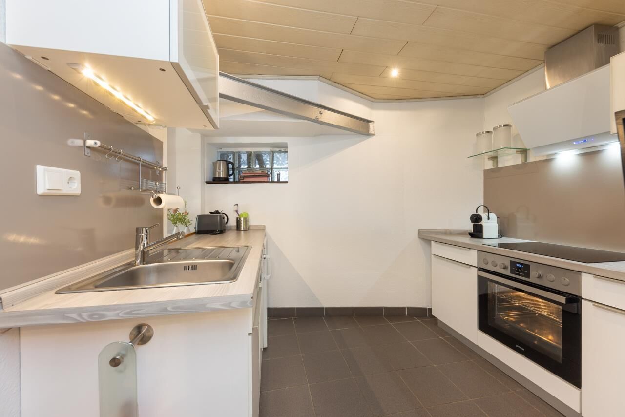 A modern kitchen with a built-in oven, stainless steel sink, and a window above the counter.