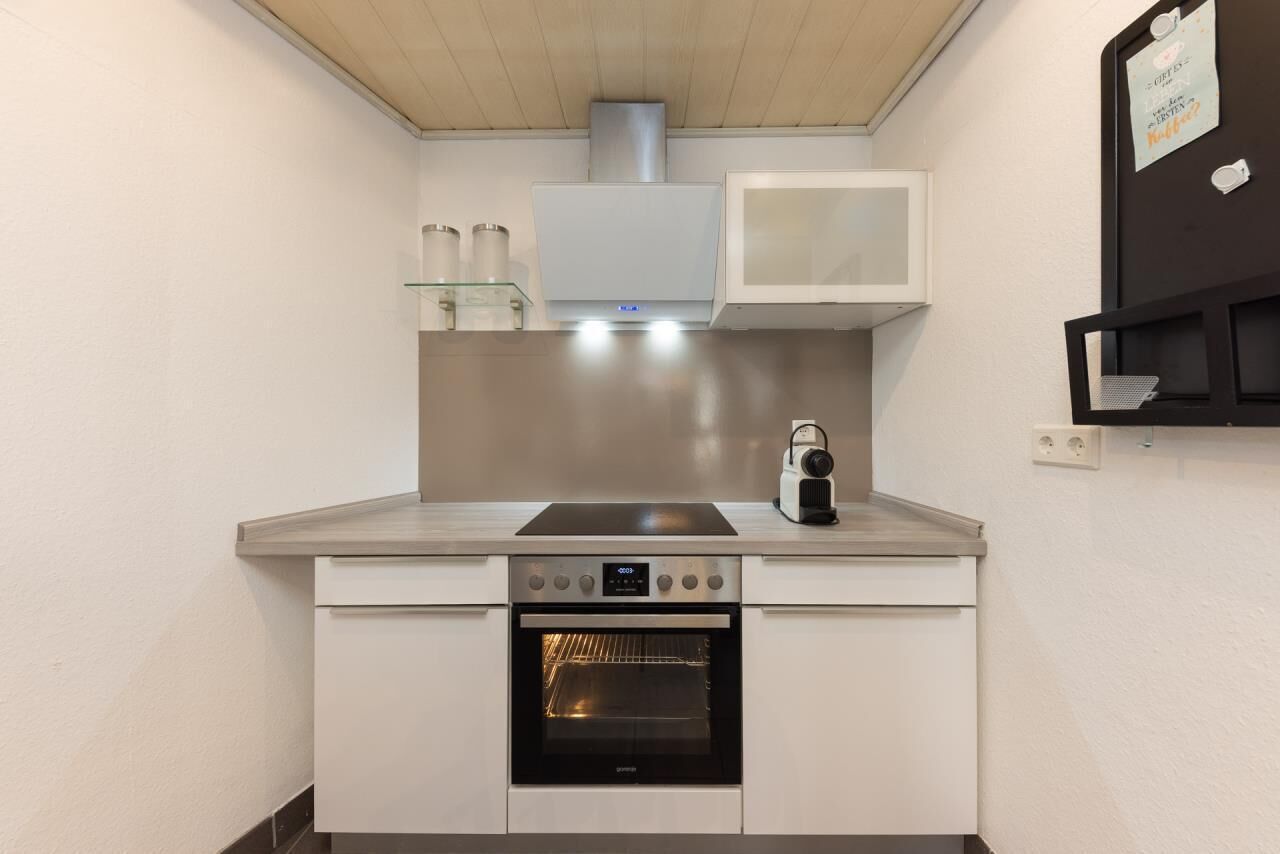 Una cocina compacta con horno integrado, microondas y campana extractora de acero inoxidable.