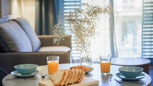 A breakfast setting with a table, bowls, a cutting board with bread, and a vase with flowers. - Aspasios Diagonal Art (Barcelona)