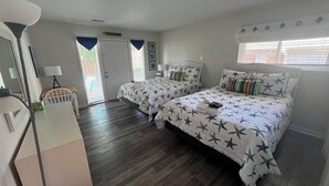 Quarto com duas camas, uma escrivaninha e uma cadeira.