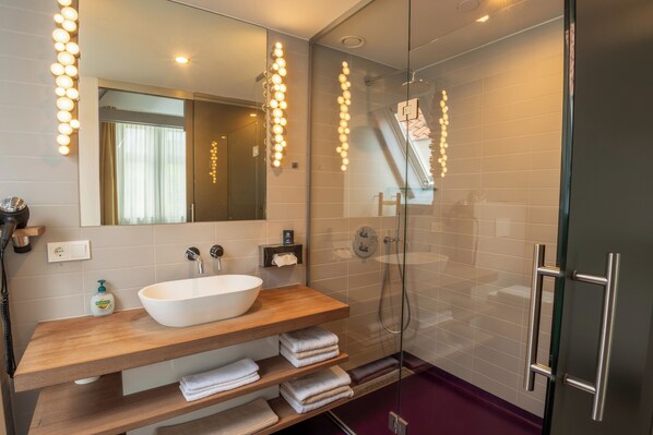 Ein modernes Badezimmer mit einem Holz-Waschtisch, einem großen Spiegel und einer Duschkabine aus Glas.