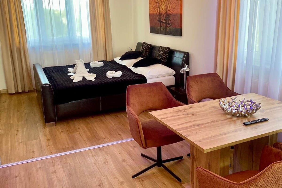 Habitación de hotel con cama, mesa de comedor y sillas.