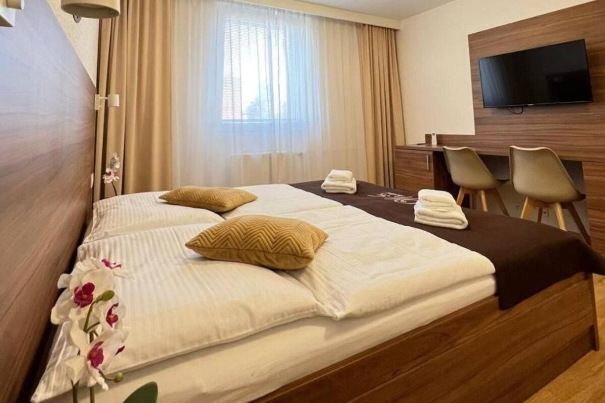Habitación de hotel con cama, escritorio, televisor y ventana con cortinas.