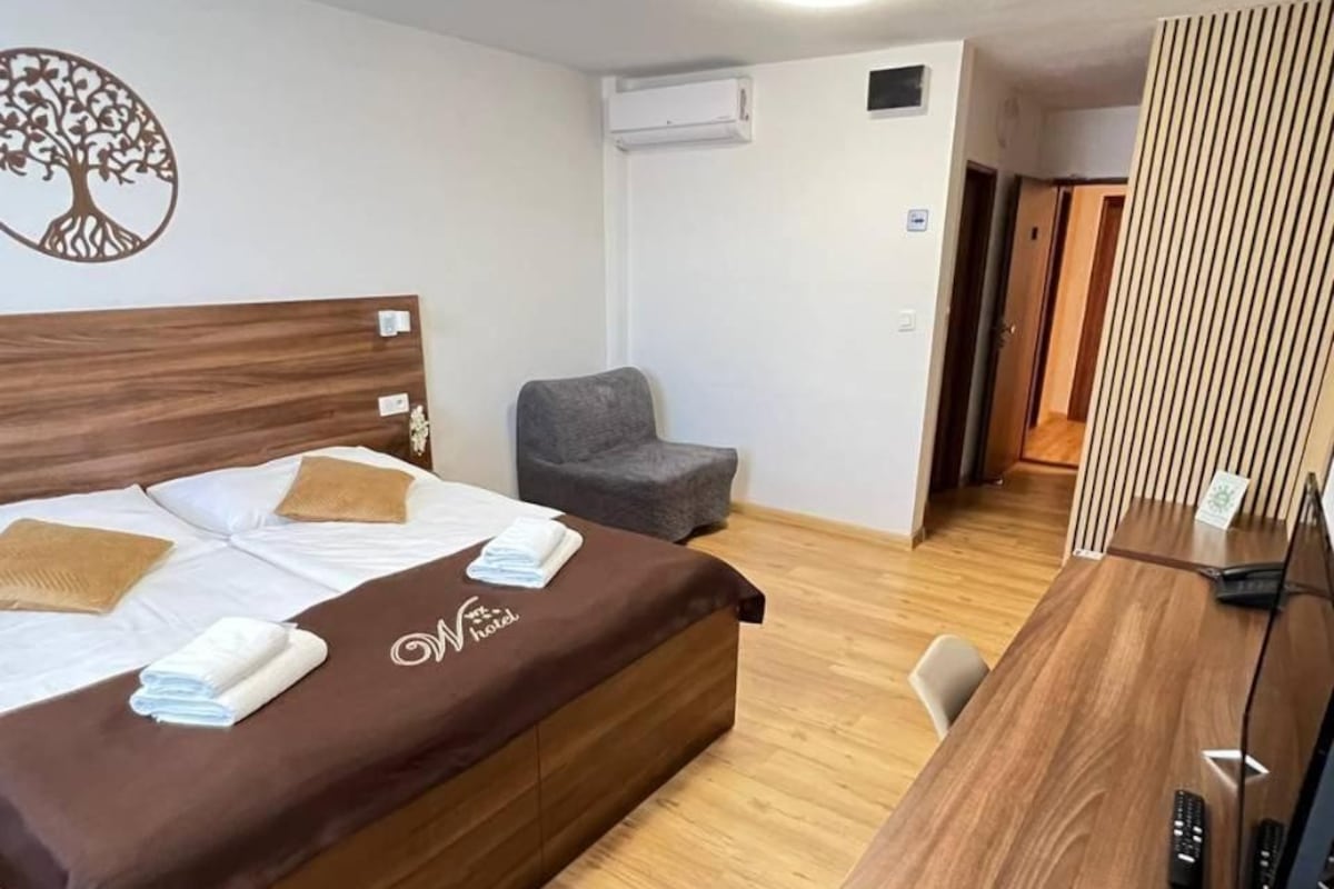 A hotel room with a bed, a desk, a chair, and a small seating area.