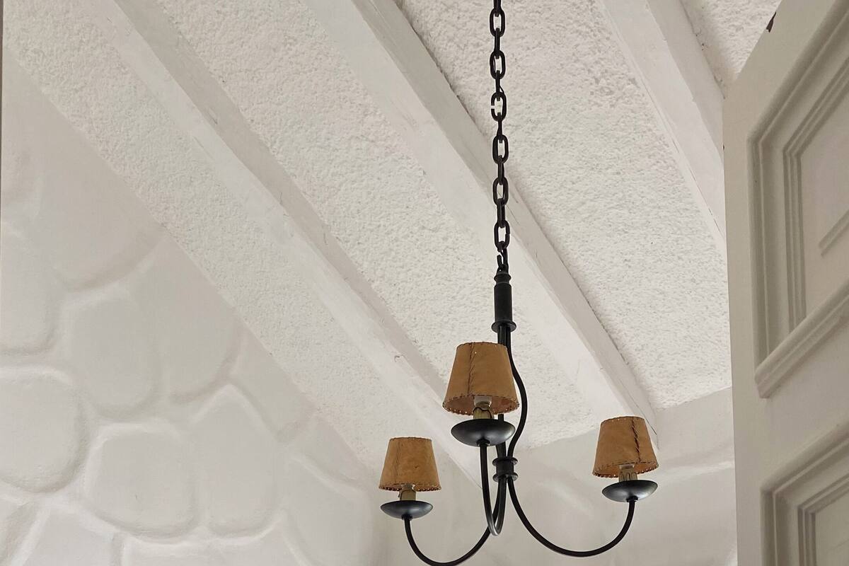 Un dormitorio con dos camas, una araña, un cuadro en la pared y una ventana con cortinas.