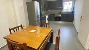 Cocina compacta con electrodomésticos modernos, una mesa de comedor con sillas y vistas al exterior a través de un ventanal.