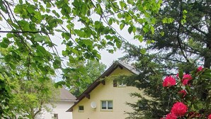 A house with a well-maintained lawn and a garden with red flowers. - Haus am Wald Quietly located vacation apartment on the ground floor with terrace (Bad Tabarz)