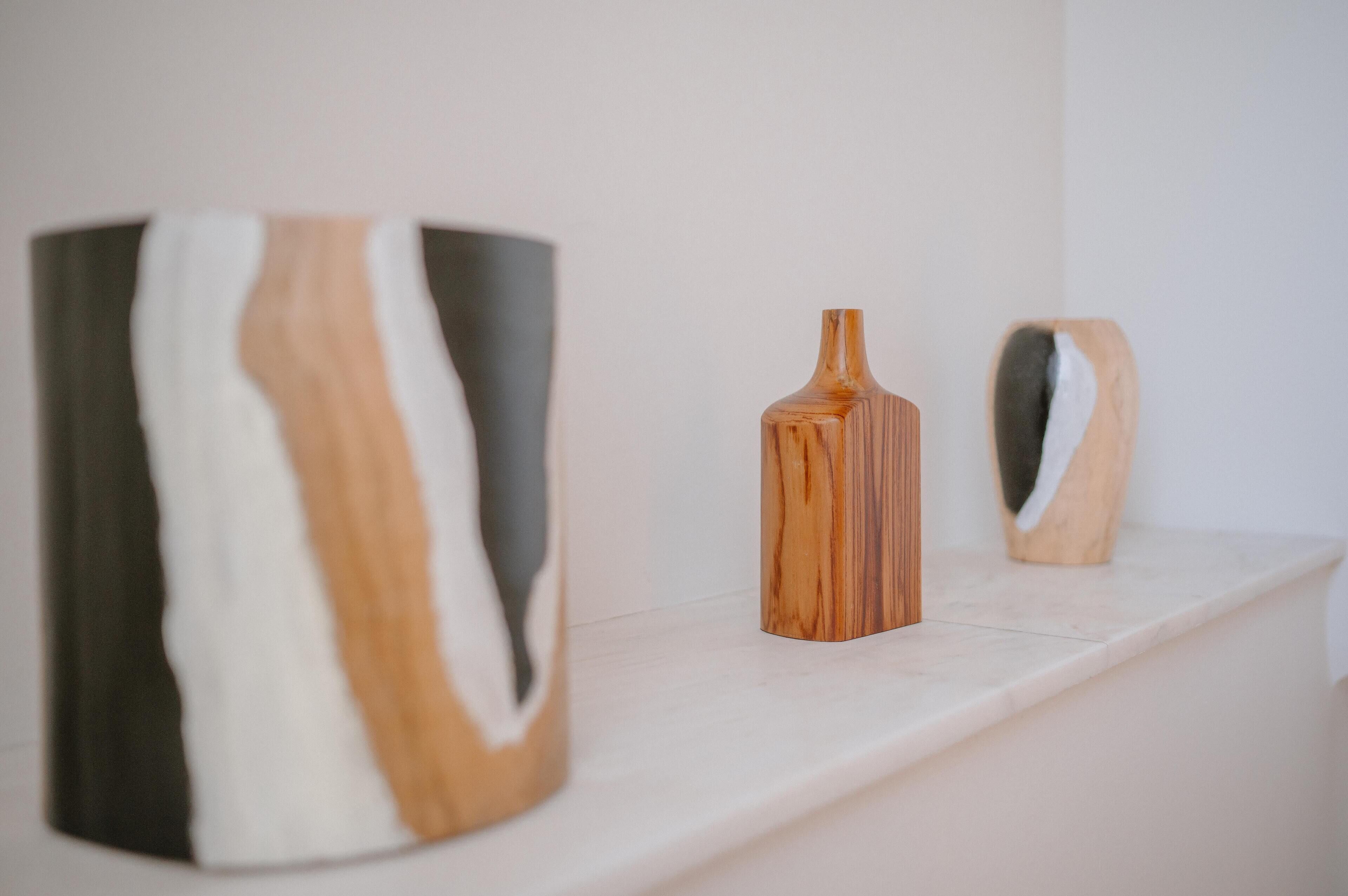 Three wooden vases on a white shelf.
