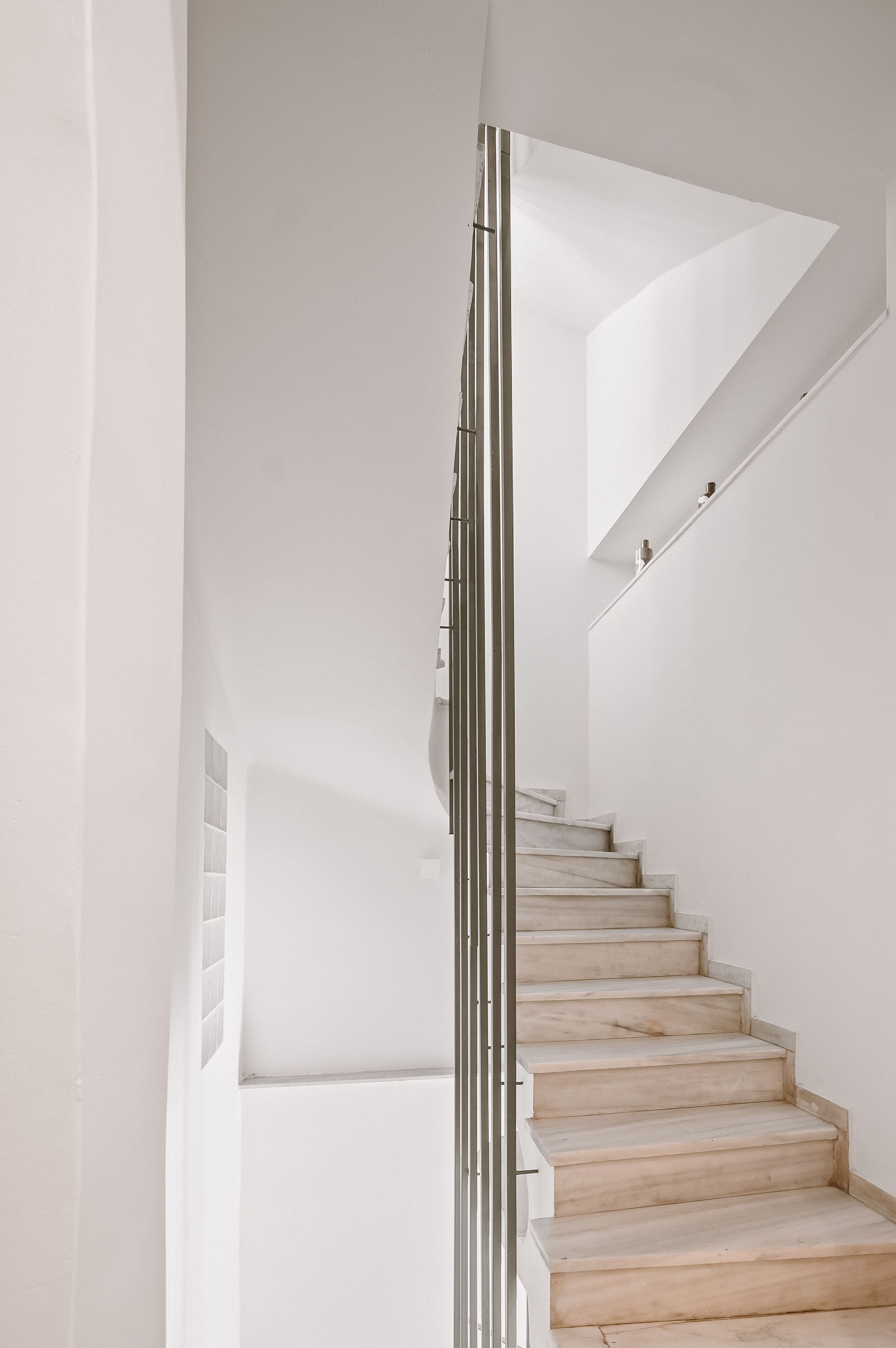 A modern staircase with a minimalist design, featuring a metal handrail and light-colored steps.