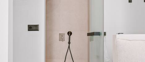 A modern bathroom with a glass shower enclosure, a wooden vanity, and a white towel.