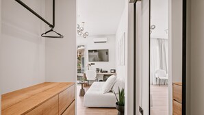 A modern living room with a wooden bench, a white sofa, and a dining area with a table and chairs. - Plānis Str Urban Suites by Semavi (Heraklion)