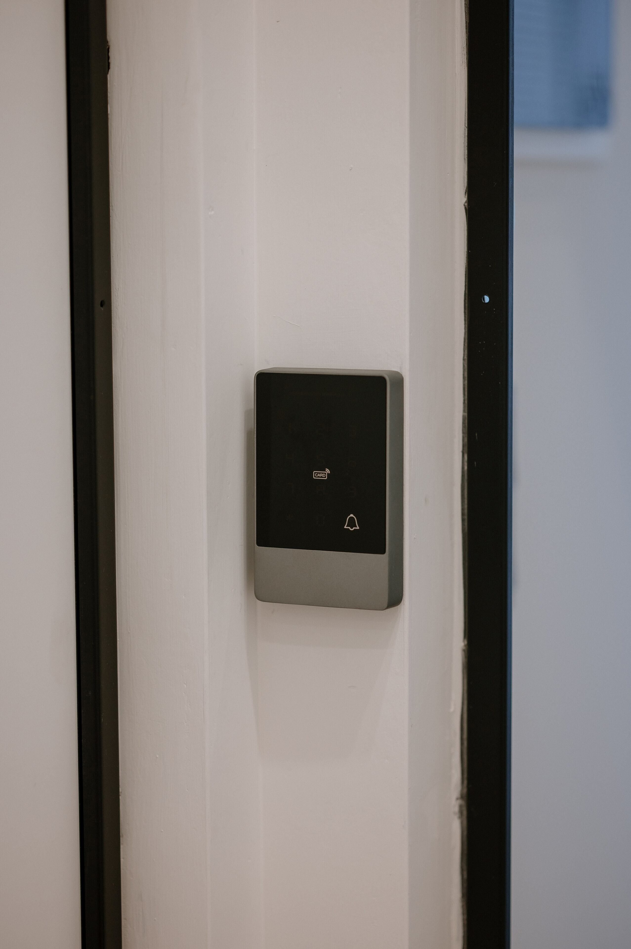 A door with a modern, rectangular intercom system mounted on the wall.
