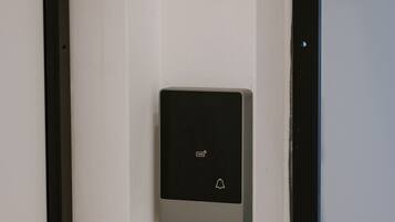 Une porte dotée d’un système d’interphone moderne et rectangulaire, fixé au mur.