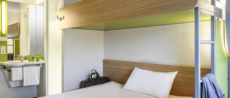 Una cama litera con cabecera de madera, una mesita de noche con una revista y una maleta.