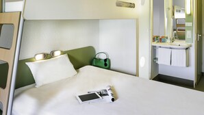 Un lit superposé avec une table de chevet, un sac vert et une tablette posée sur le lit.