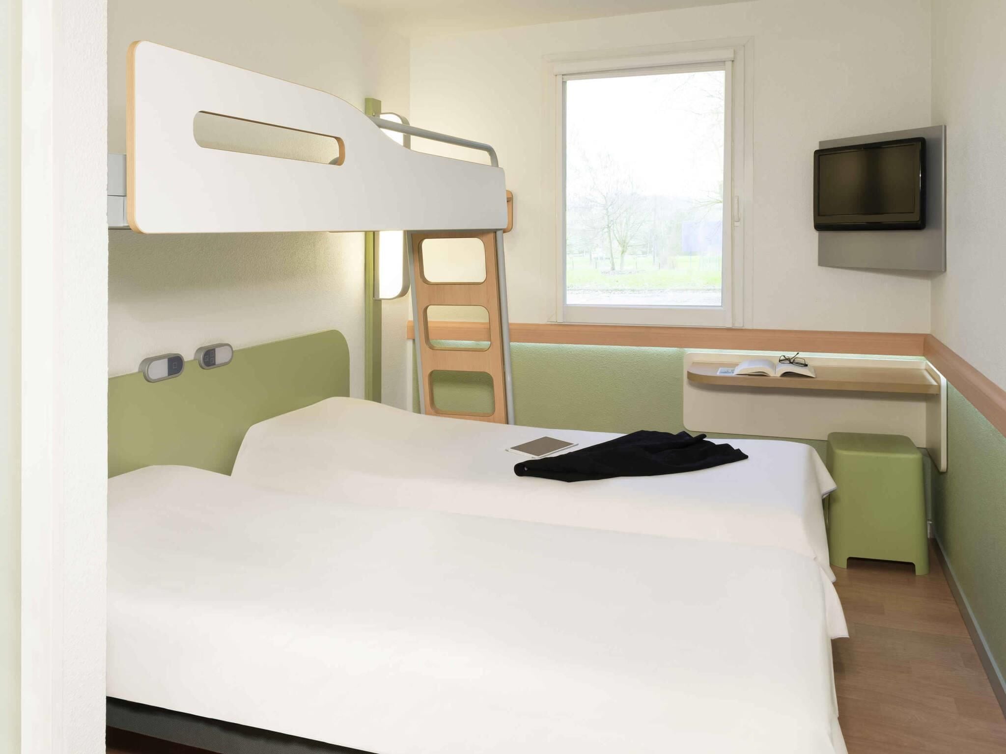 Una cama individual superpuesta con escritorio y televisor en una habitación de hotel.