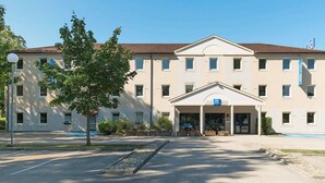 Un bâtiment doté d’une entrée centrale, de nombreuses fenêtres et d’une enseigne indiquant qu’il s’agit d’un hôtel ibis budget.