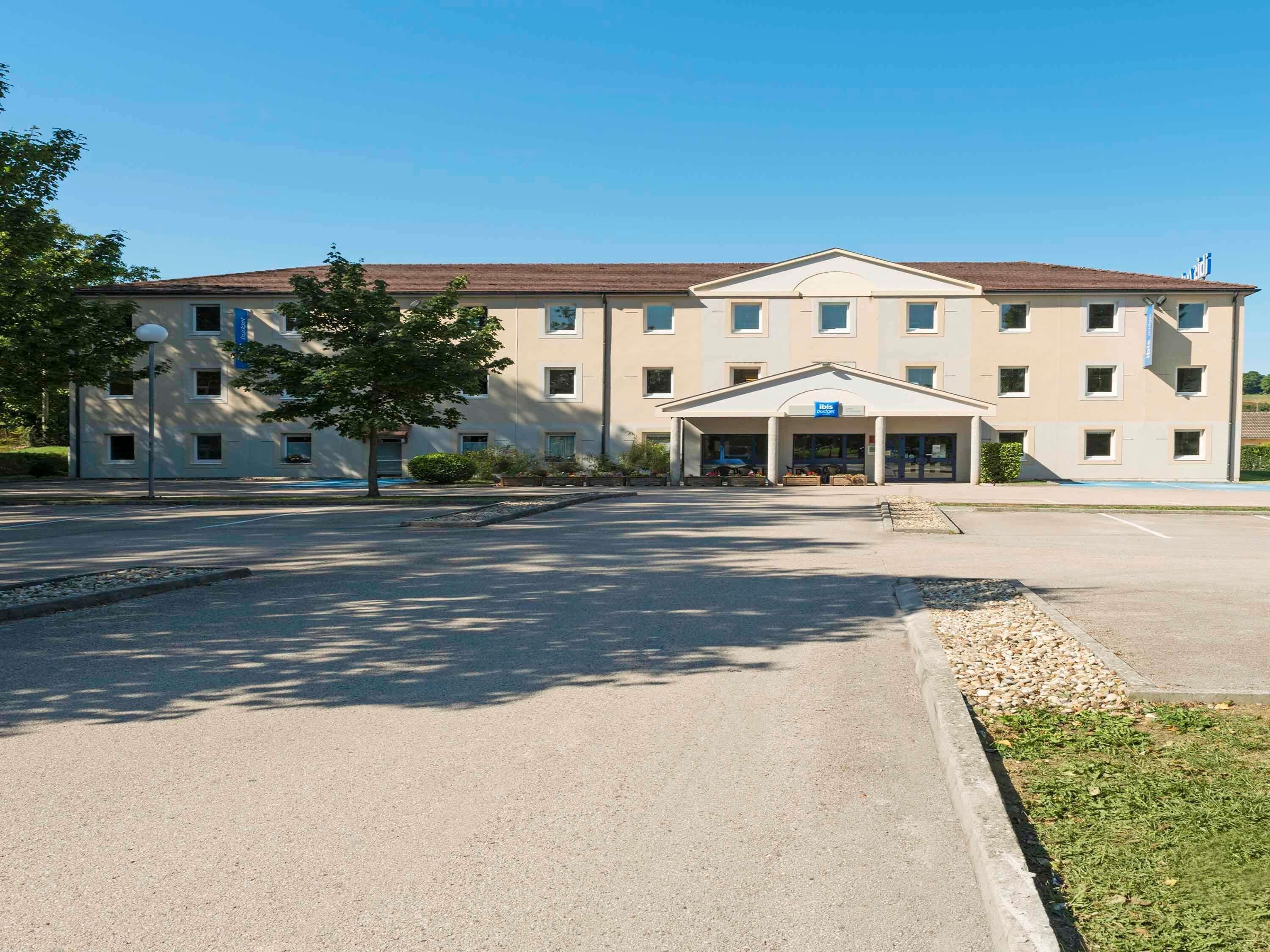 A large, multi-story hotel with a central entrance and a covered waiting area.