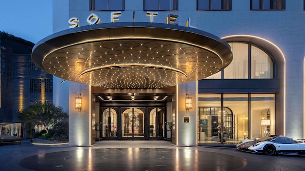 A hotel entrance with a large illuminated canopy, a modern facade, and a car parked outside. - Sofitel Shanghai North Bund (Shanghai)