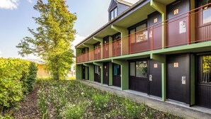 A modern building with a green facade, multiple doors, and a red railing on the upper level. - greet Brussels Airport Zaventem (Zaventem)