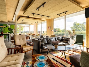 Un interior moderno con un sofá, sillas, una mesa de centro y ventanas amplias que ofrecen vistas al exterior.