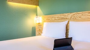 Habitación de hotel con cama, almohadas y una tableta sobre la cama.