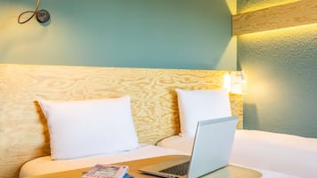 A hotel room with a bed, a laptop, and a book on the bedside table.