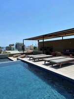 Una piscina al aire libre, sillones reclinables de piscina