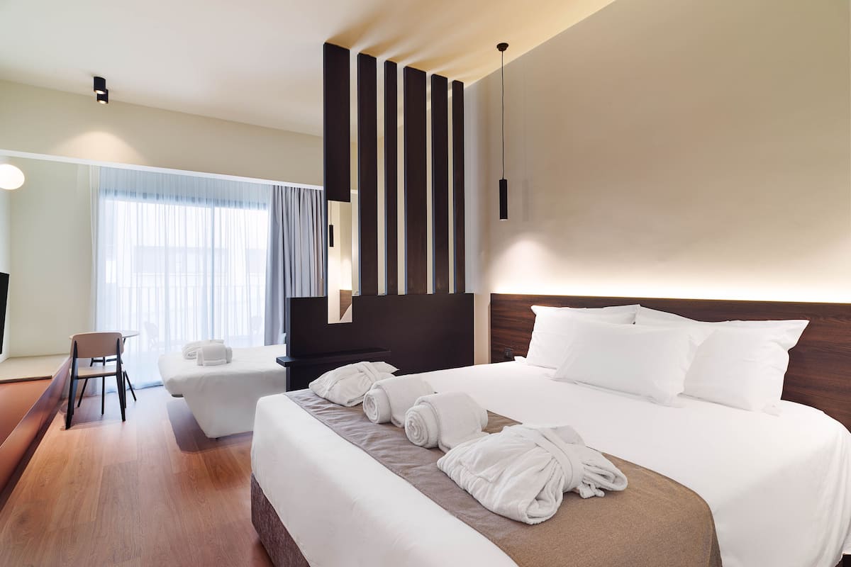 A modern hotel room with a large bed, a desk, and a chair.