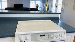 A kitchen with a white stove, a blue countertop, and a window with curtains.