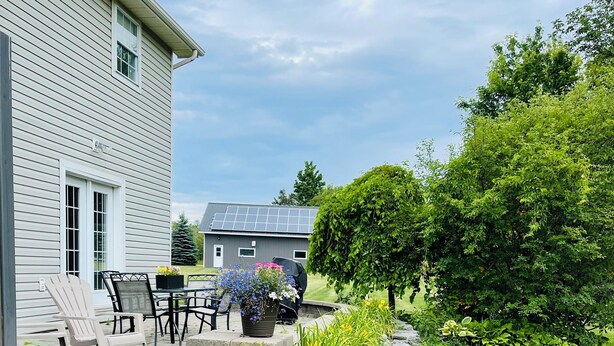 A house with a patio area, outdoor seating, and a garden with various plants.