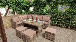 A wicker outdoor seating area with a table set for dining, surrounded by greenery. - Haus am Wald Ruhig Gelegene Ferienwohnung mit Großem Garten (Bad Tabarz)