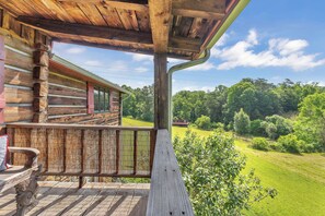 A wooden cabin with a porch overlooking a green landscape. - 25p Mountain Retreat w Pool/Hottub/Sauna/Movie Theatre/Gameroom 5m from DT (Asheville)