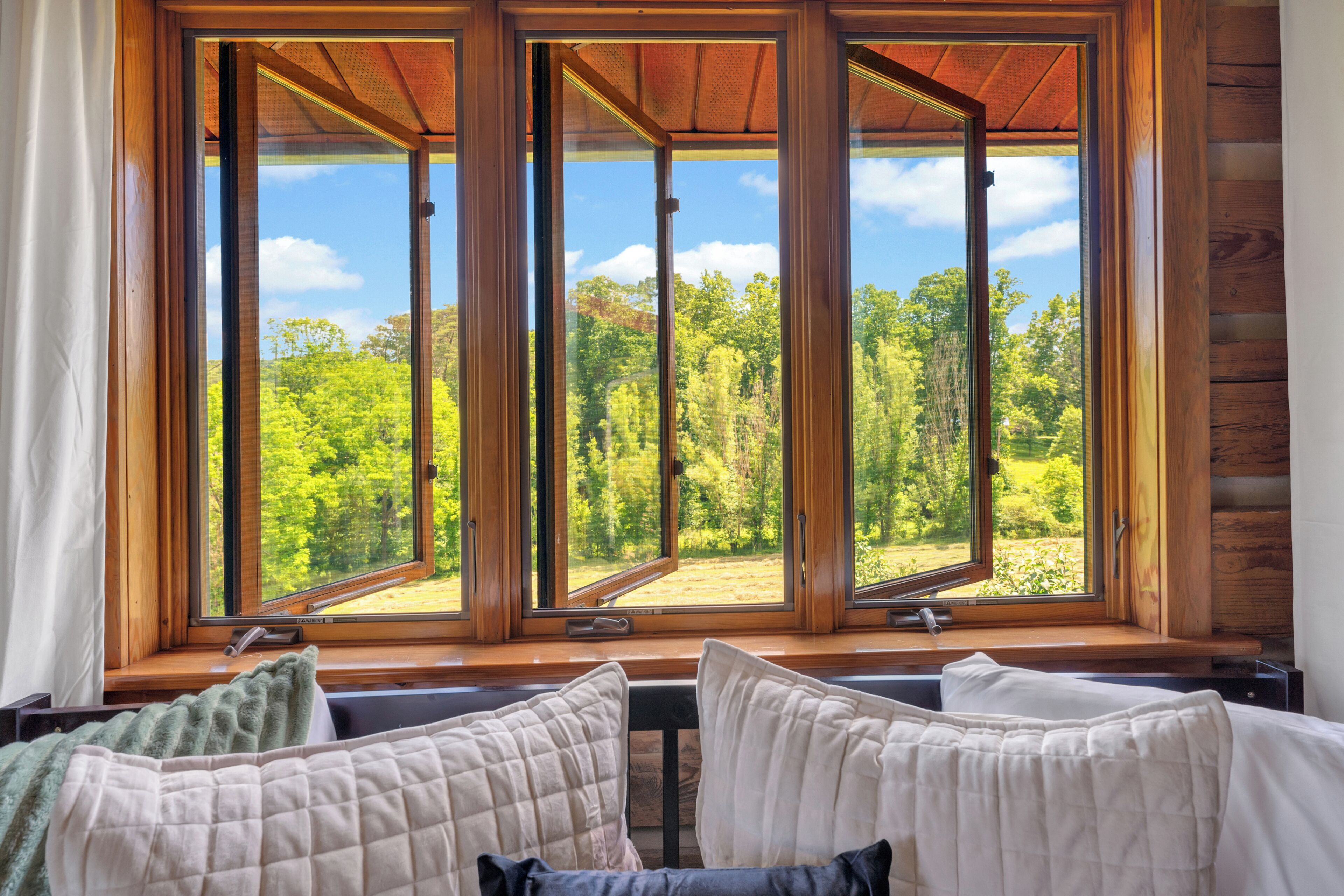A room with a large window overlooking a forested area.