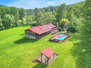 Ett stort hus med ett rött tak, en swimmingpool och en inhägnad uteplats.