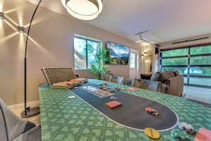 Une pièce comprenant une table de poker, des chaises, une grande fenêtre et un tableau accroché au mur.